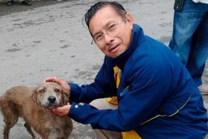 Reportero Jacinto Romero acaricia a perro callejero empapado. Imagen en honor a su vida injustamente terminada.